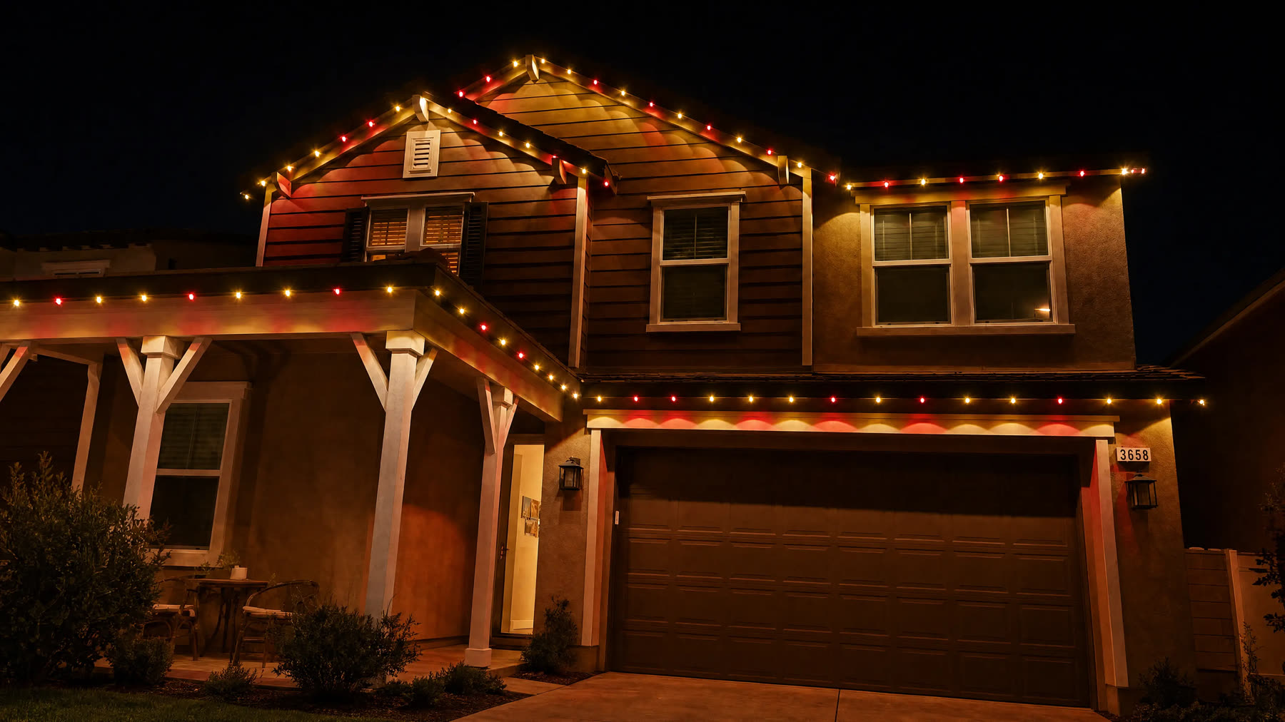 A two-story home with red and gold lights along every roofline